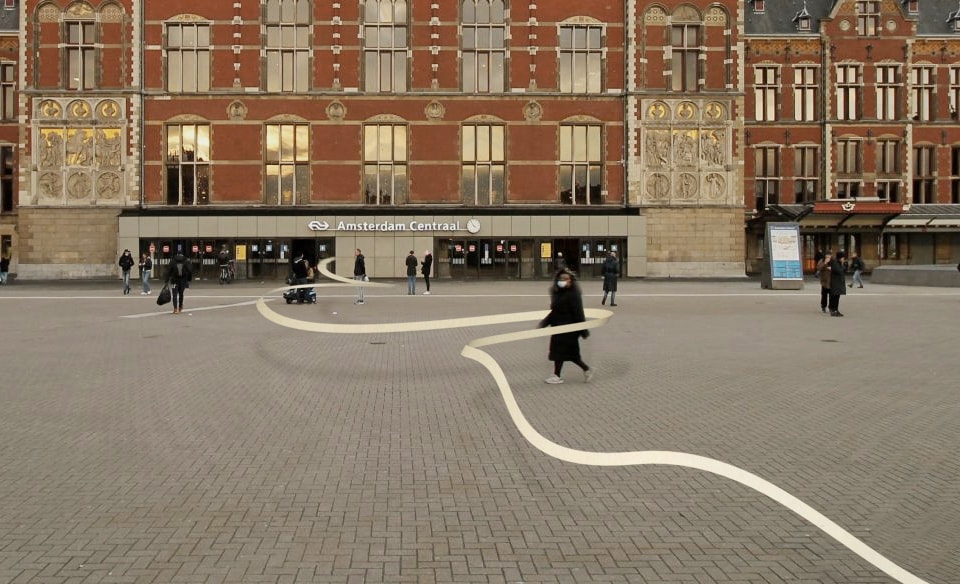 A sketch render of a giant scroll of paper, running dozens of meter in length across an open square and then entering the central station of Amsterdam.